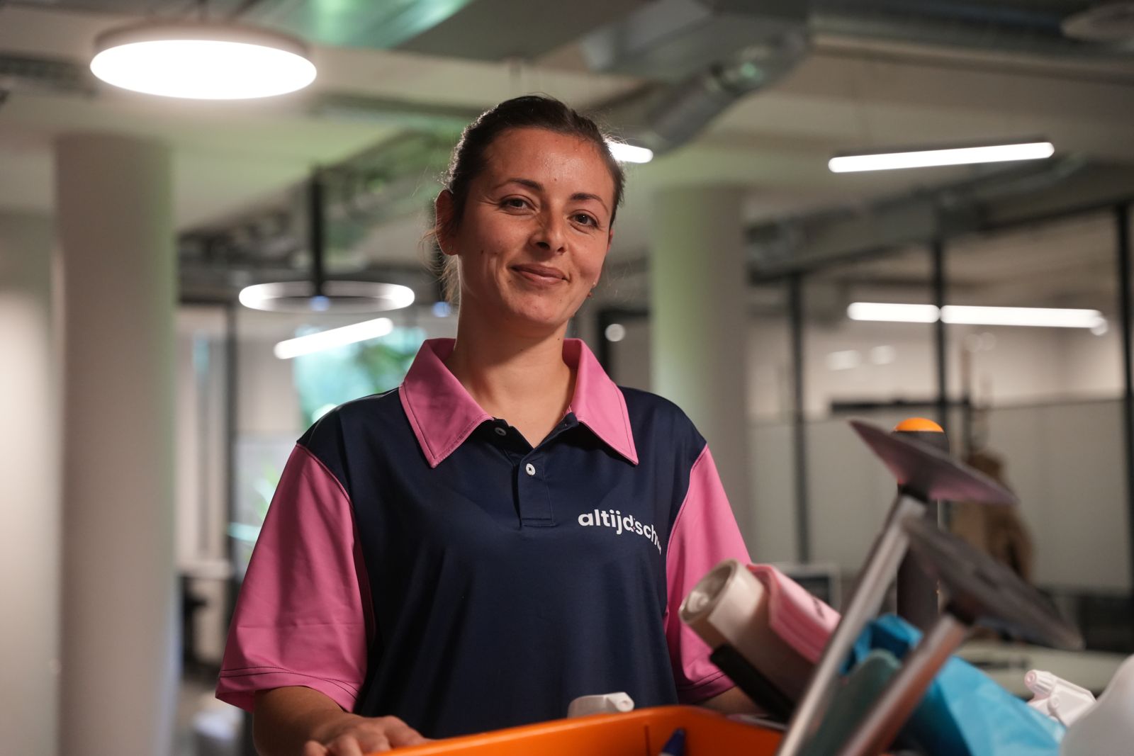 Lachende medewerker van Altijdschoon met schoonmaakemmer