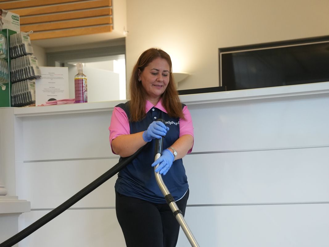 Medewerker van Altijdschoon stofzuigt bij de receptie in Leidschendam-Voorburg
