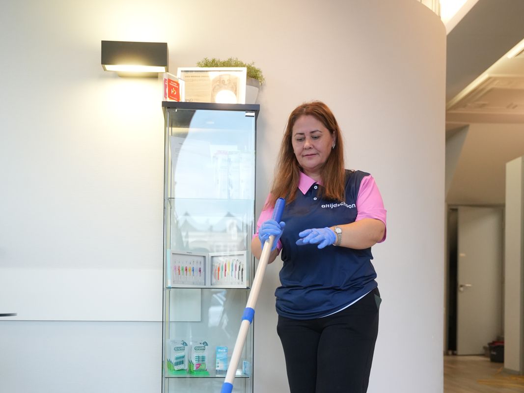 Medewerker van Altijdschoon reinigt de vloer met een vlakmop