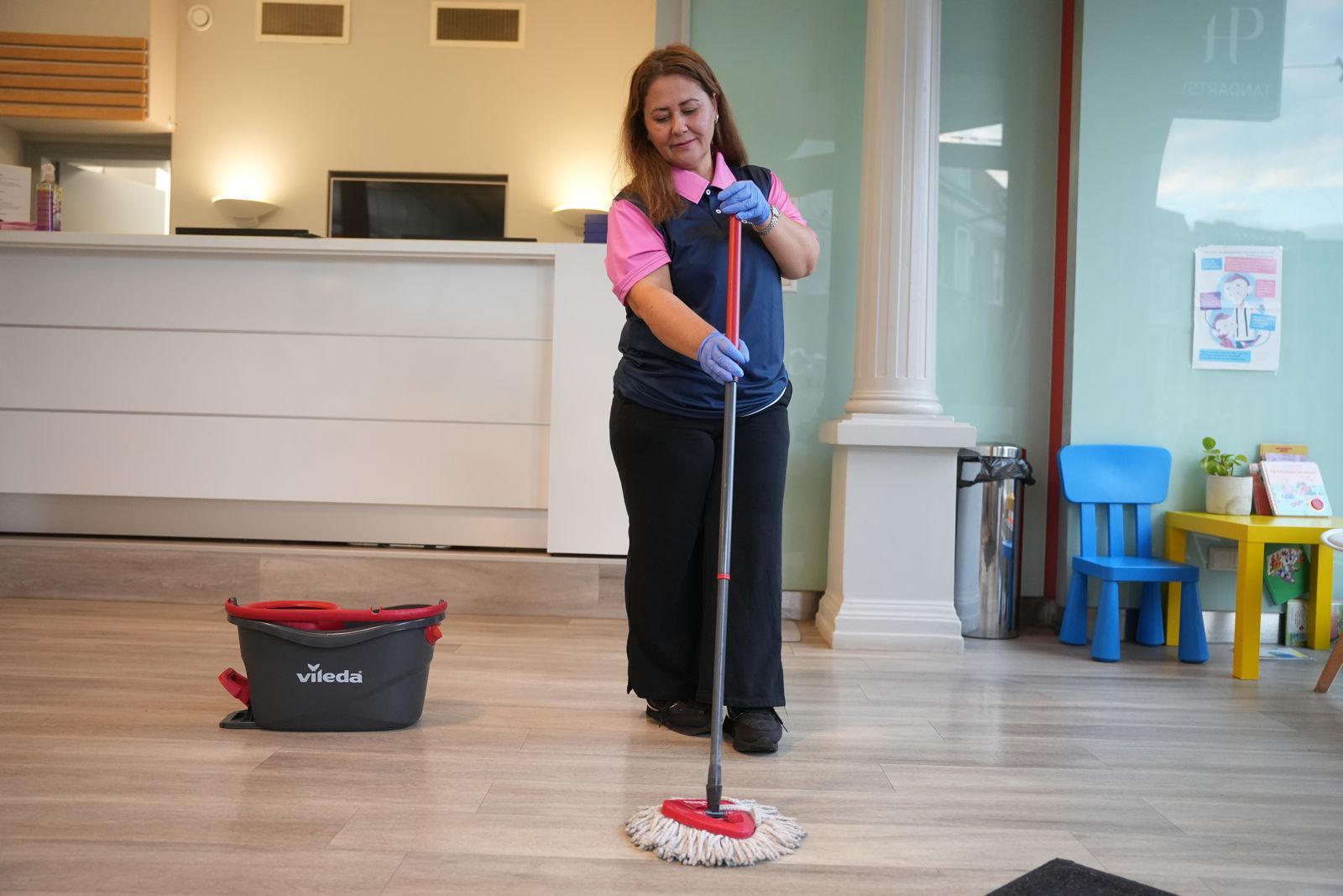 Medewerker van Altijdschoon met mop en emmer in de ontvangstruimte